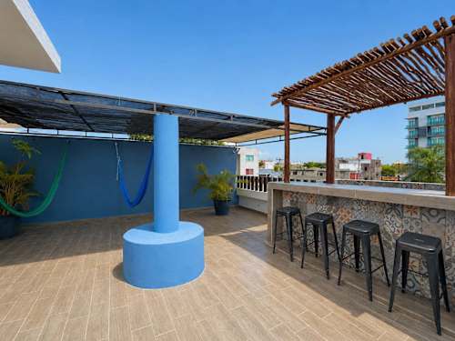 Open rooftop deck with a bar counter, stools and a pop of blue, plenty of room to lounge and mingle