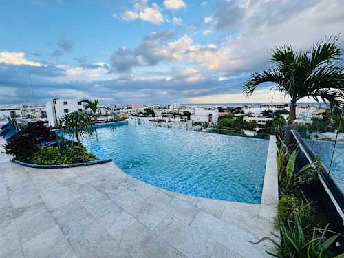 Rooftop infinity pool with loungers and lush views, your sunny escape above Playa del Carmen
