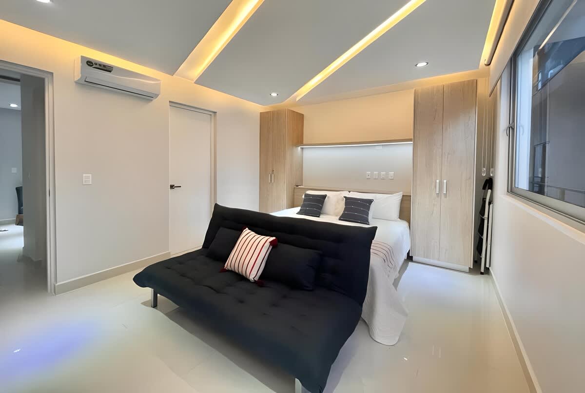 Open-plan studio living area with sofa bed, Smart TV and AC