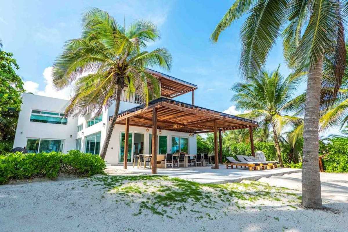 Beachfront villa exterior surrounded by tropical gardens and palms