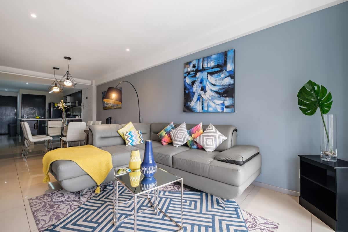 Bright living room with a plush sofa, cheerful accents and floor-to-ceiling city views, easy upscale living