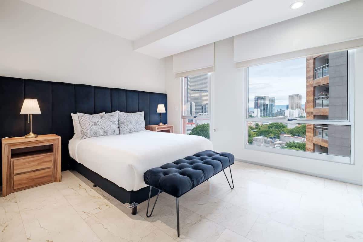 Restful bedroom with a tufted headboard and sweeping city views, a calm retreat above Nuevo Polanco