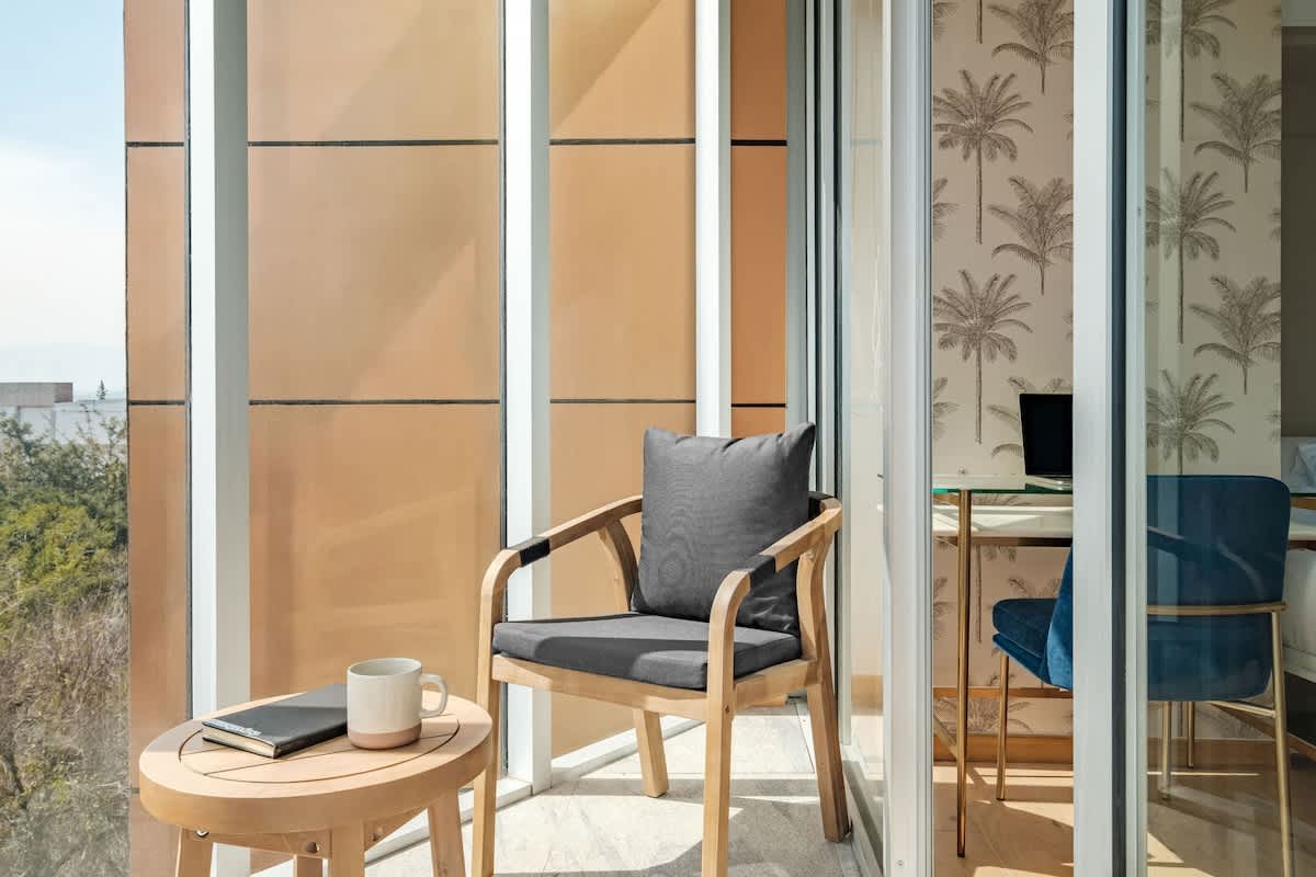 Sunny balcony with seating and floor-to-ceiling glass, a bright perch above Roma Norte