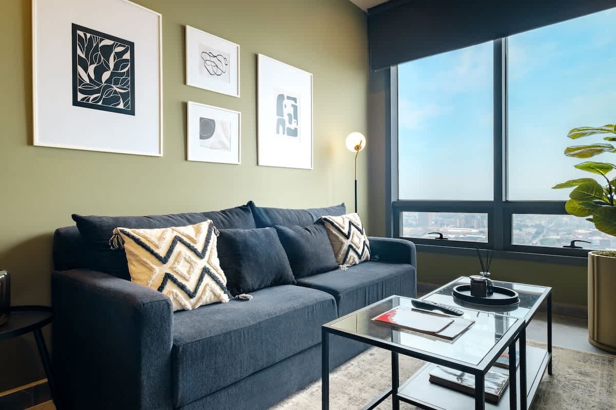 Bright living room with a plush sofa, curated art and big windows framing Reforma views