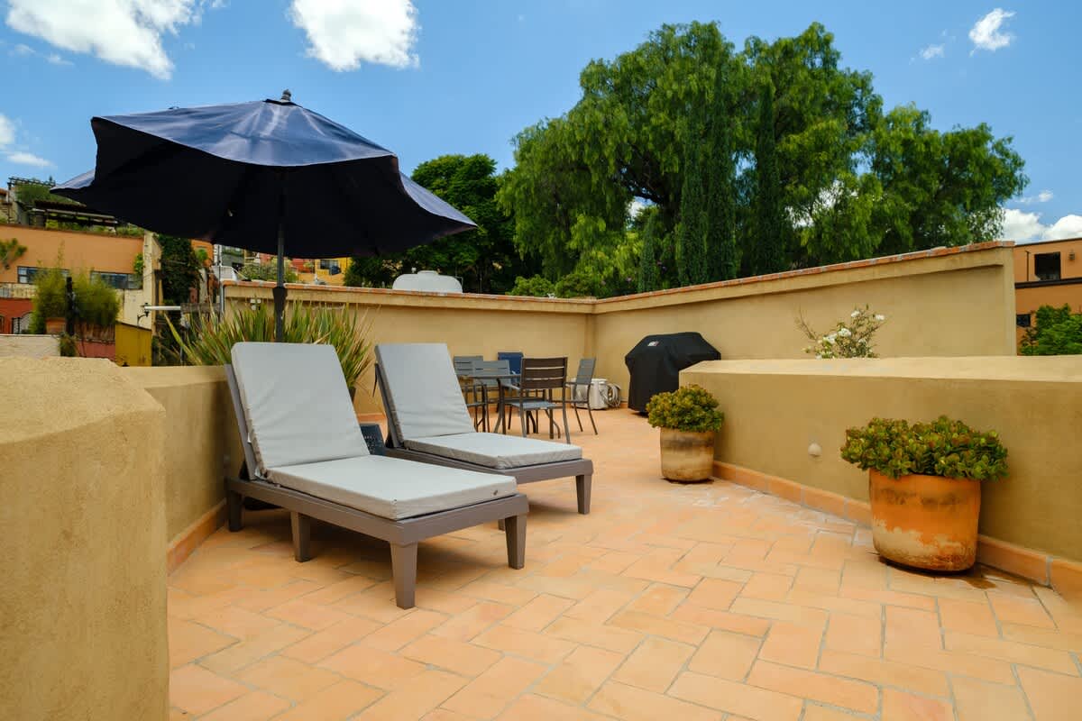 Spacious rooftop lounge with sun loungers and an umbrella, your private escape above the city center