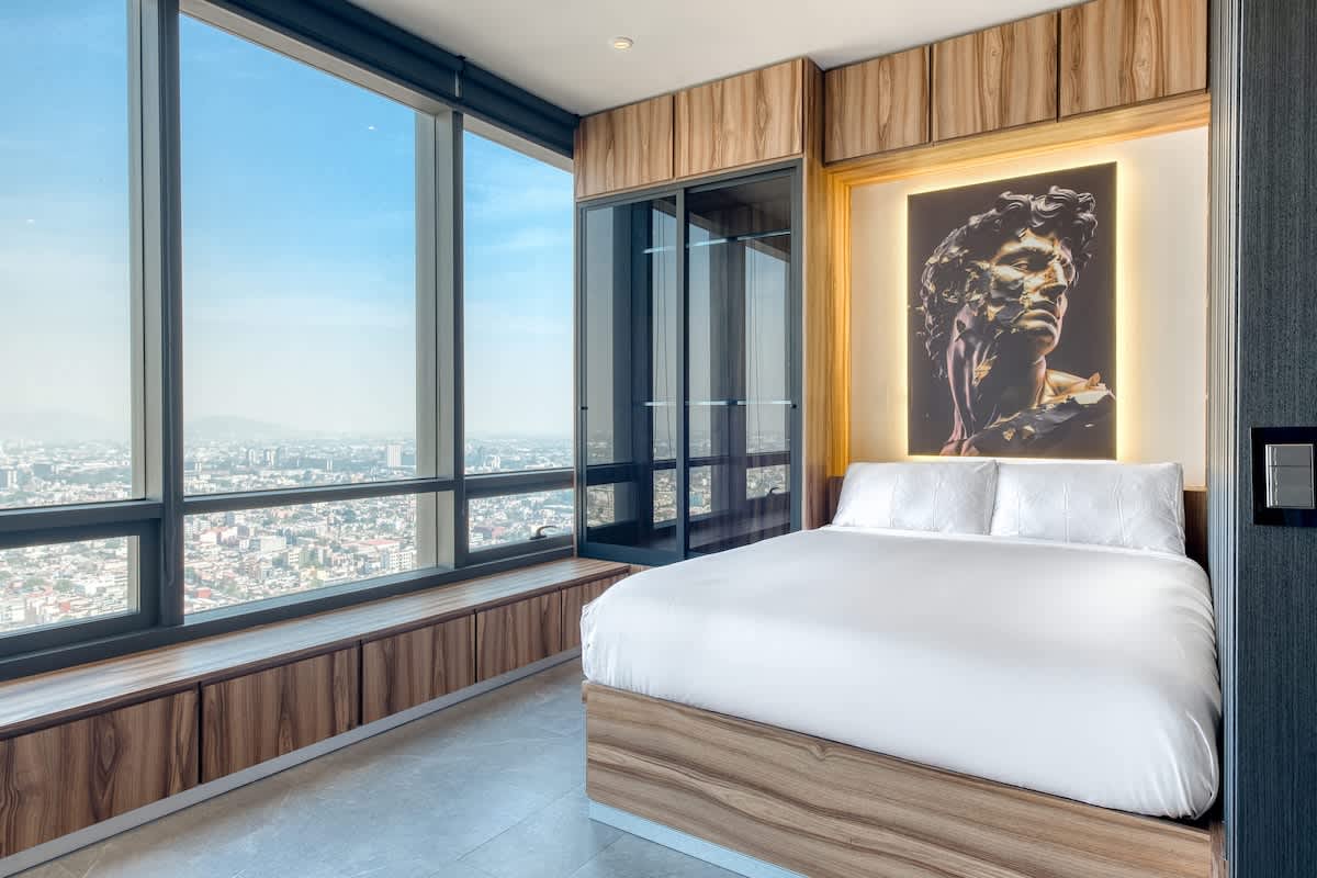 Serene bedroom with a crisp white bed and art deco accents, wake to sweeping Reforma views
