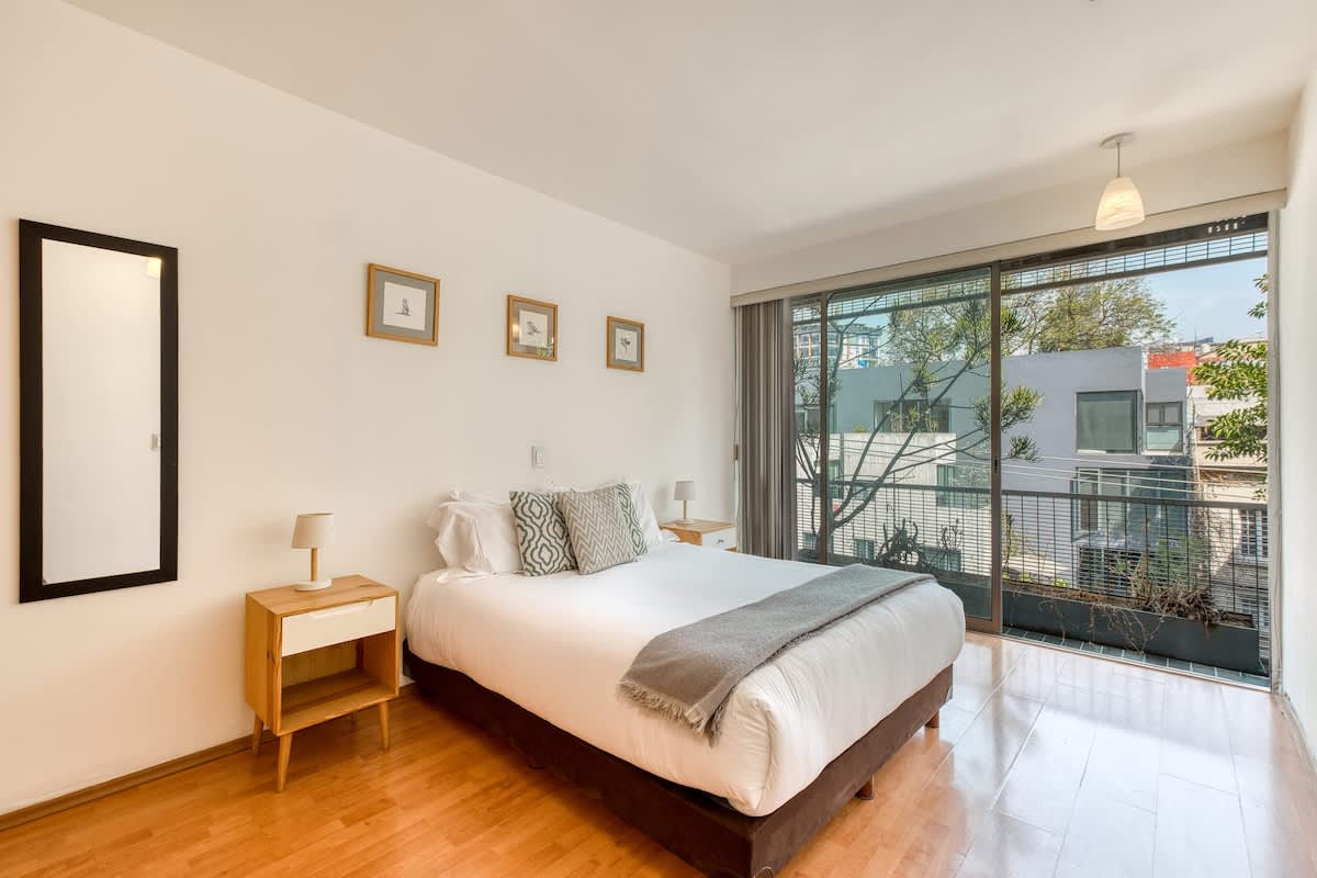 Restful bedroom with a plush king bed and balcony light, wake up to leafy Roma Norte just outside