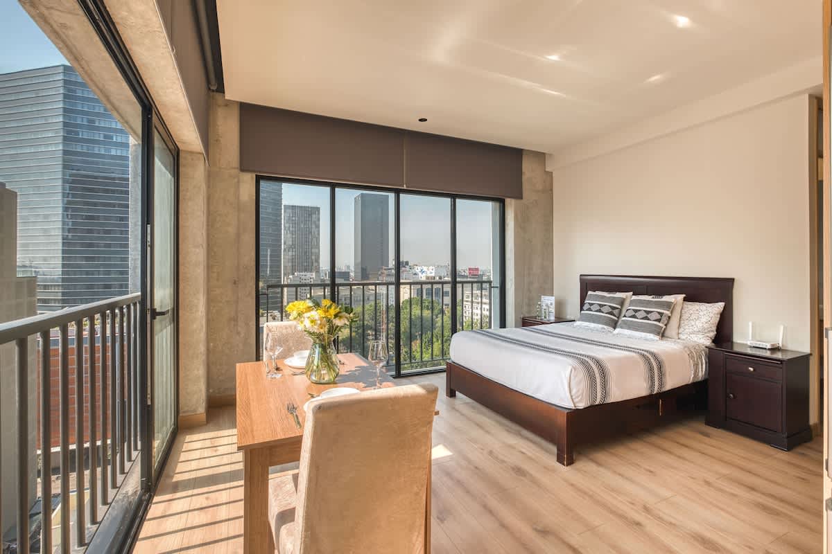 Restful bedroom with a plush king bed beside floor to ceiling windows, wake up to Centro Historico light and skyline views