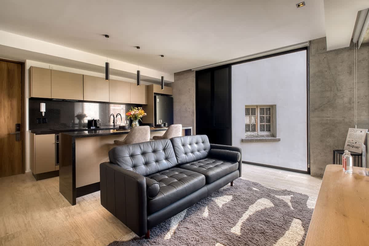 Comfortable lounge with a leather sofa and the kitchen just behind, effortless entertaining in Roma Norte