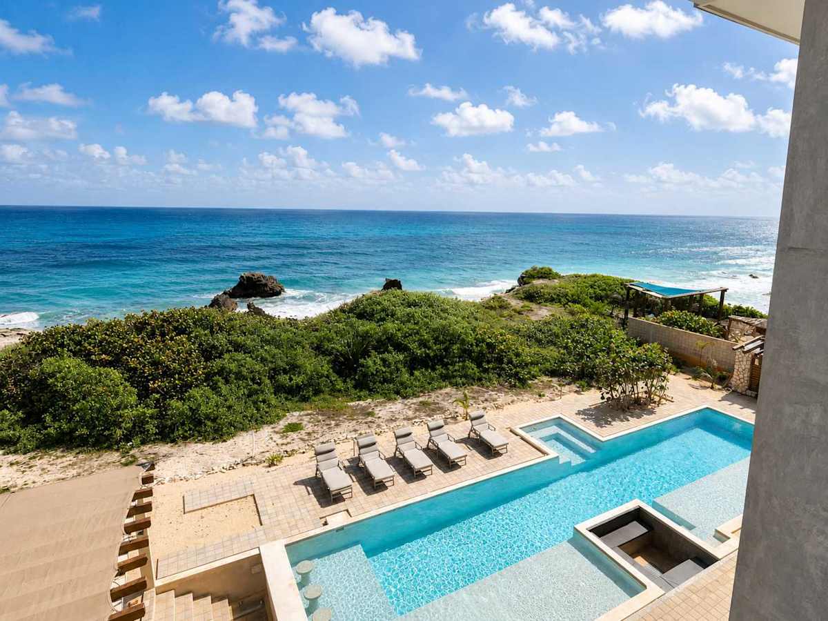 Oceanfront shared pool with sun loungers steps from the condo