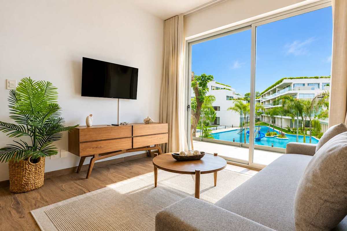 Bright living room with smart TV and large windows opening to the pool view
