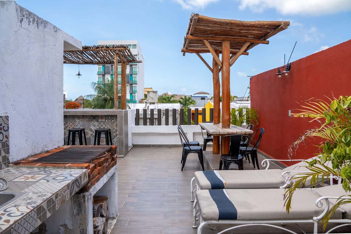 Sun loungers on the rooftop framed by a warm accent wall and greenery, room to unwind under the Caribbean sky