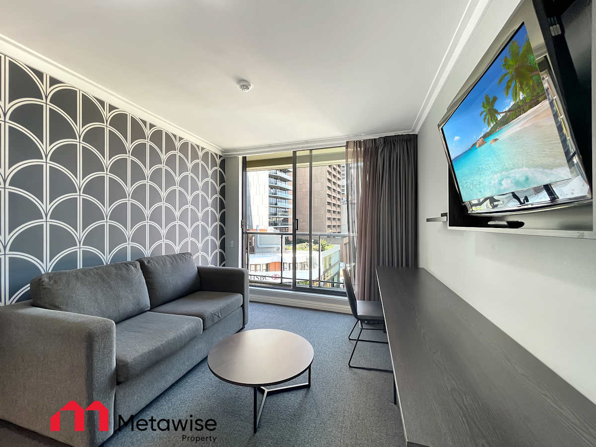 Living room with wall-mounted TV, sofa seating, and city outlook.