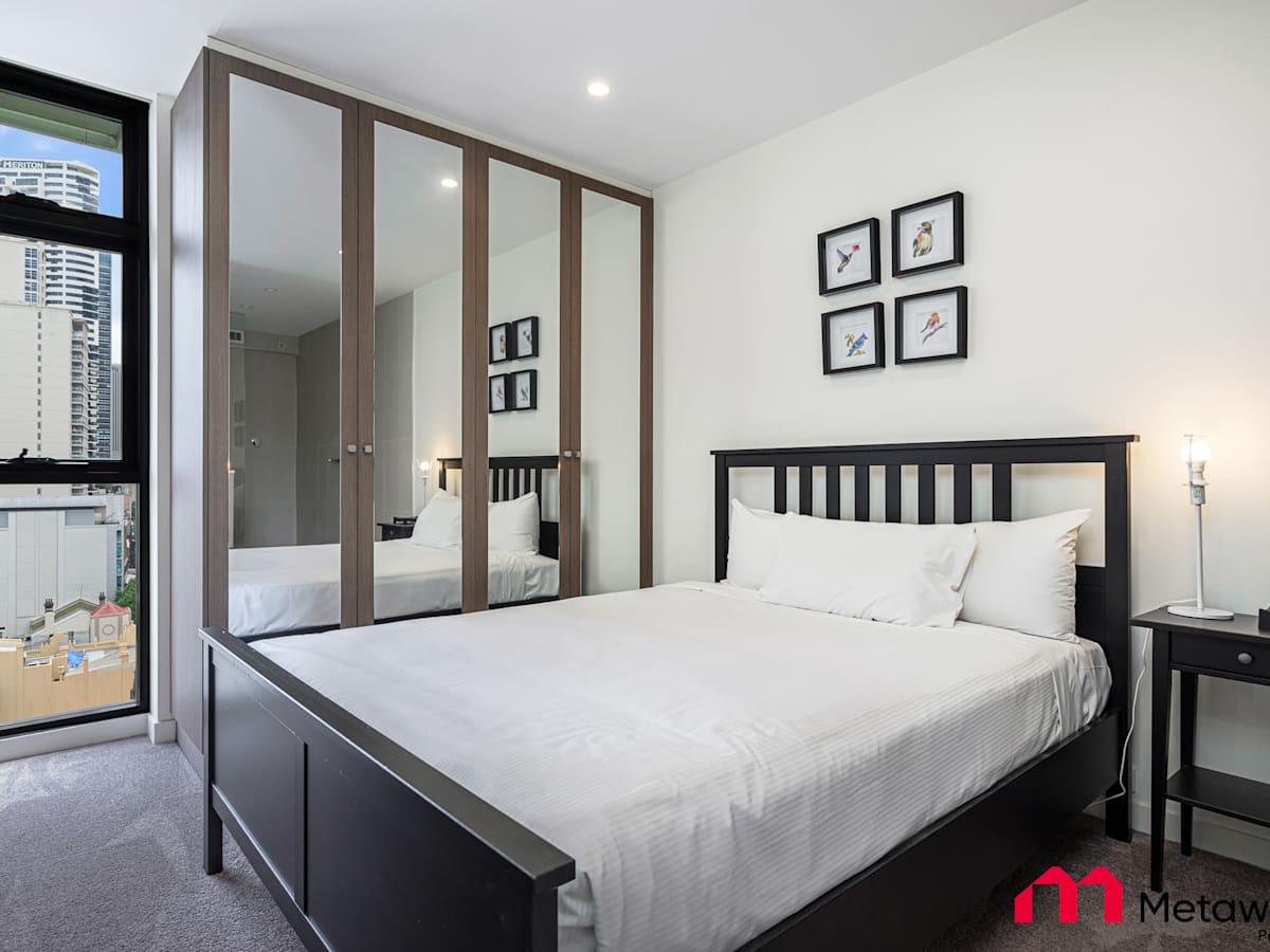 Bedroom featuring a queen-size bed, bedside tables, and balcony access.