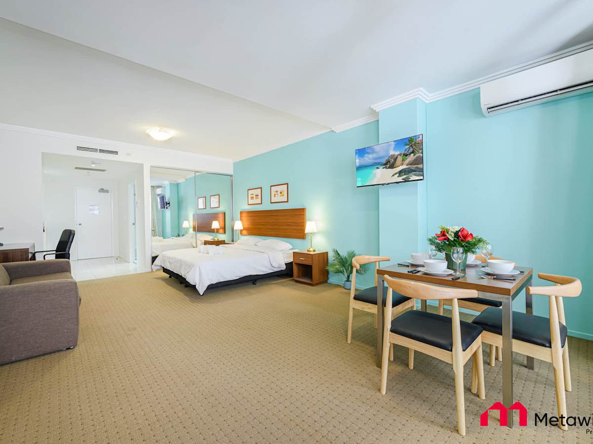 Wide view of the studio showcasing both the king-size bed  along with dining area and air conditioning.