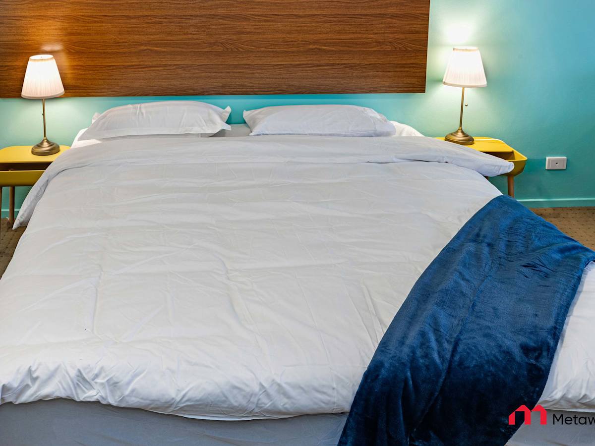 Close-up of the king-size bed with wooden headboard and bedside lighting.