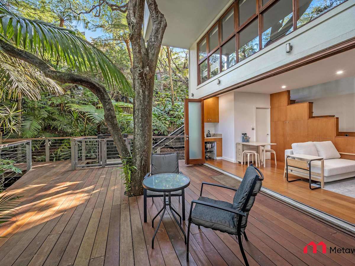 Outdoor entertaining deck with seating area surrounded by trees.