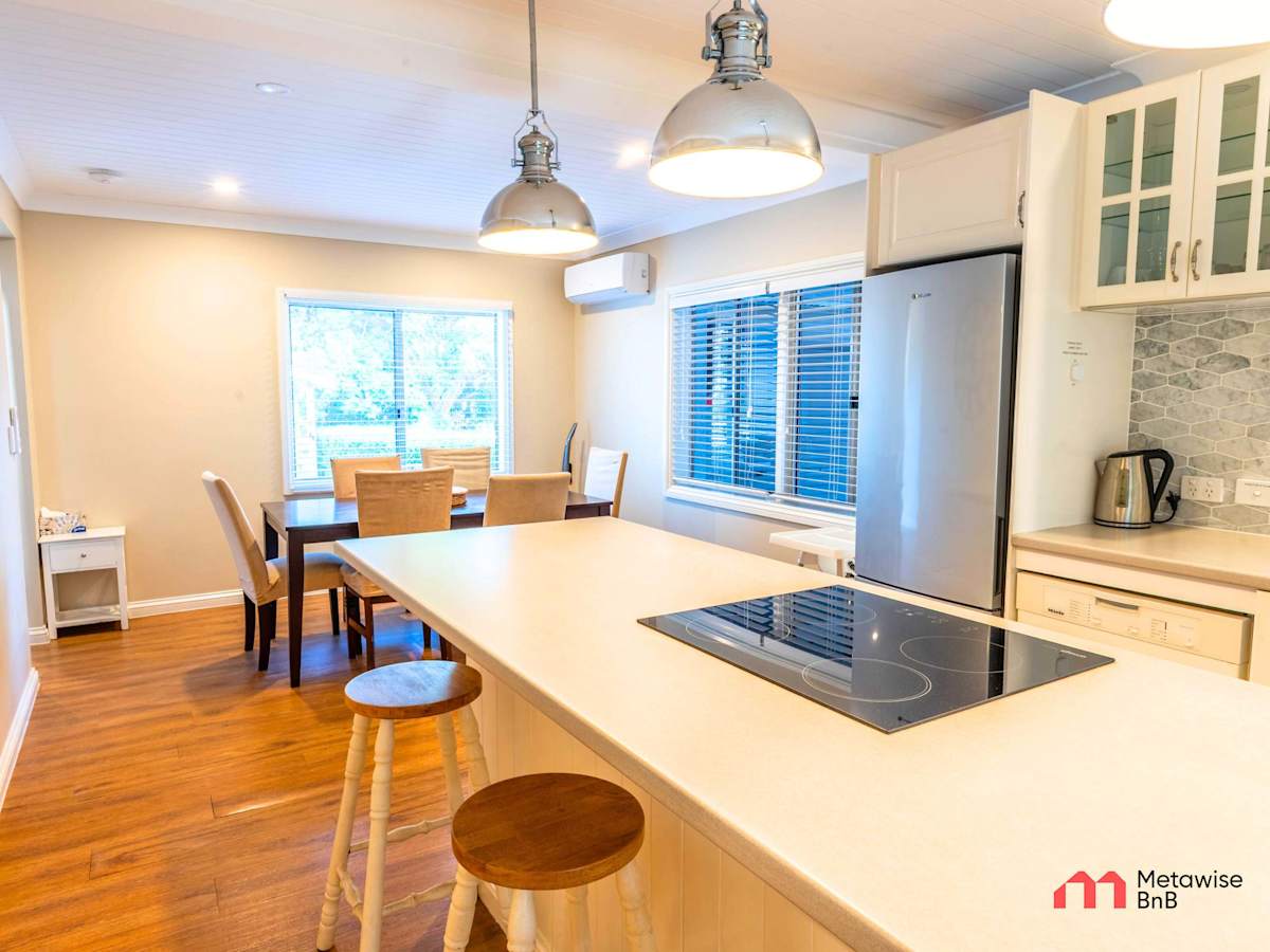 Modern kitchen with island bench, pendant lighting, and stainless steel appliances.