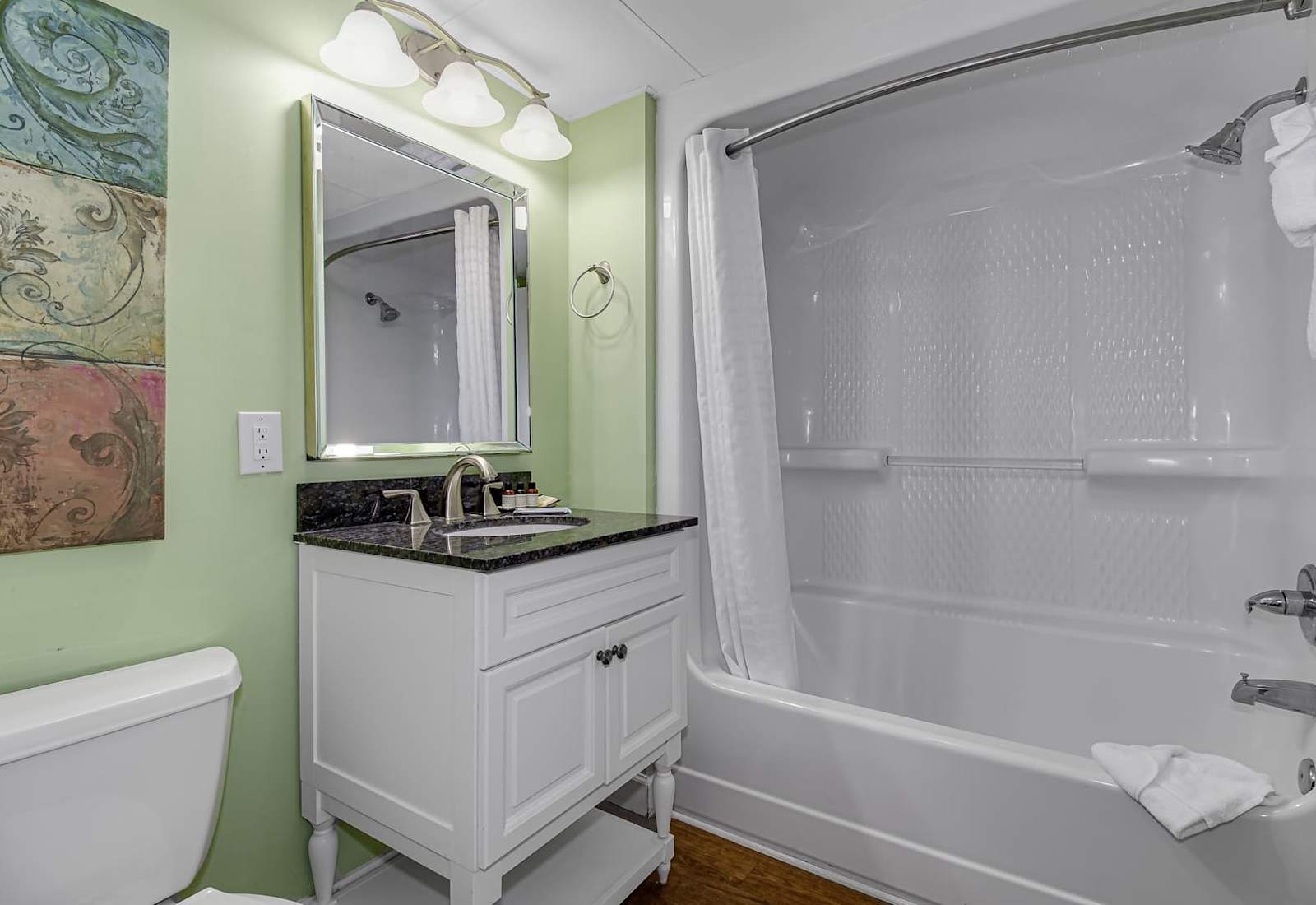 Refresh in this vibrant and clean bathroom, featuring a sleek granite vanity, modern amenities, and a pristine tub. The perfect space to unwind and rejuvenate after your coastal adventures. 