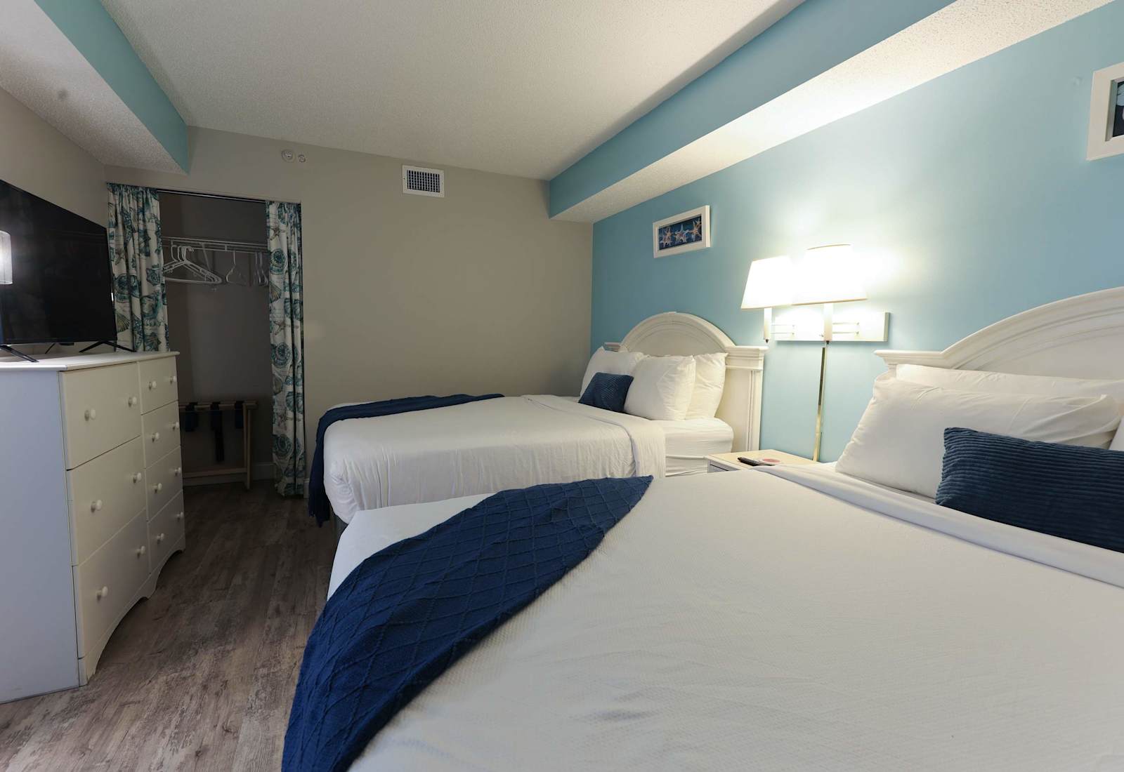 Drift into beachy dreams in this cozy, coastal-inspired bedroom featuring two comfy beds, seashell décor, and soft lighting—perfect for families or friends on a Myrtle Beach escape.