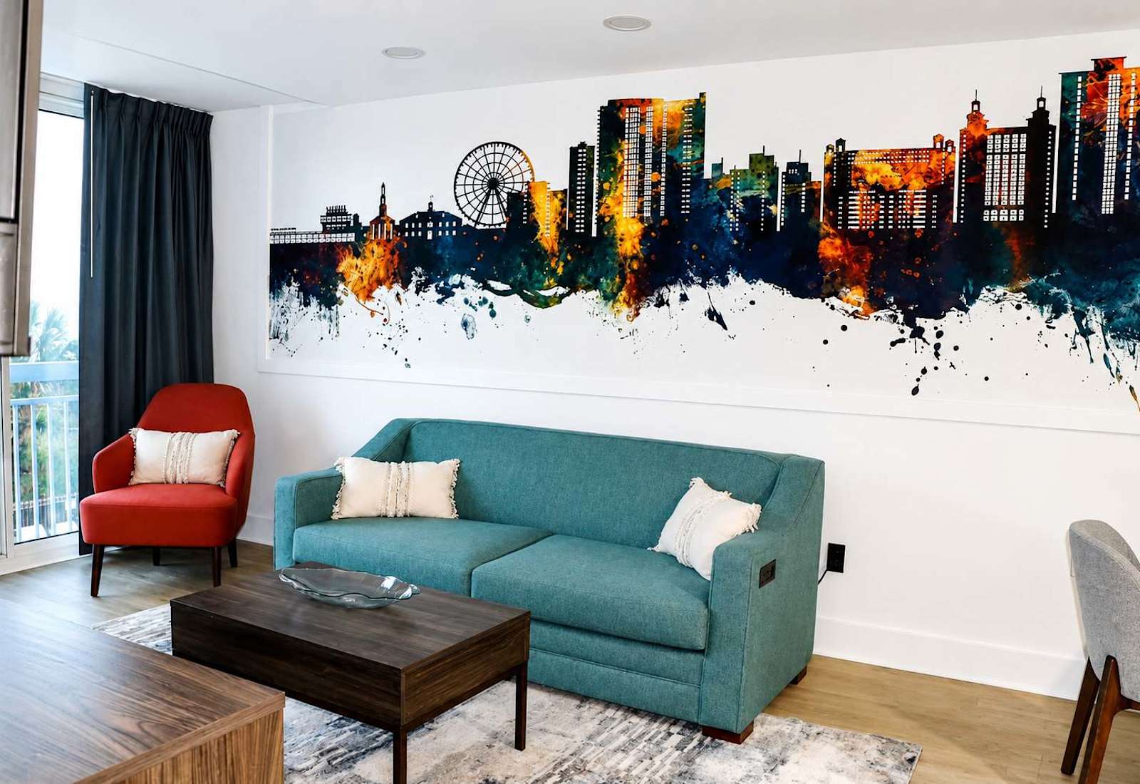 Unwind on our plush teal sofa right beneath the stunning watercolor skyline mural!