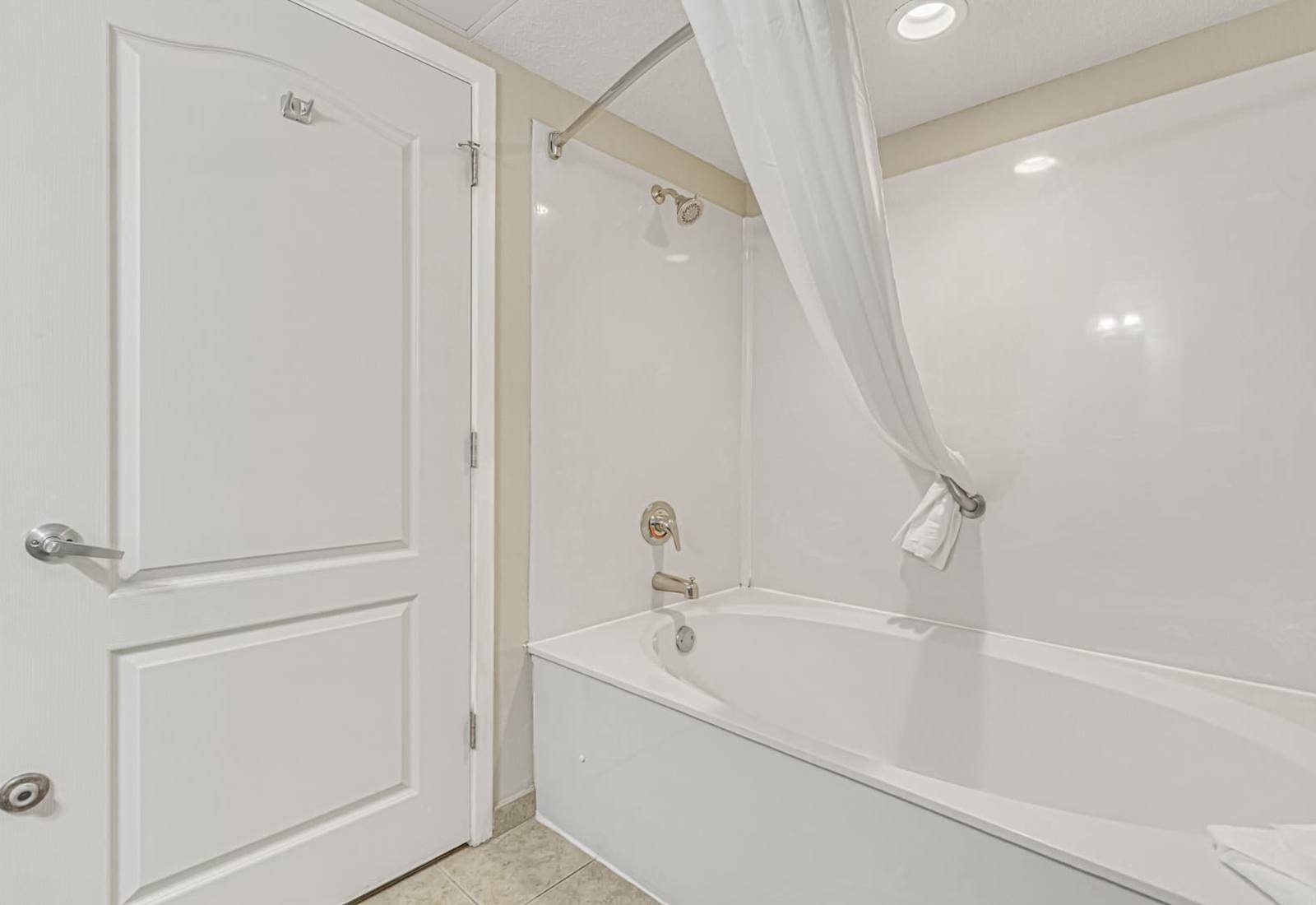 Clean shower-tub combo with a bright white finish, privacy curtain, and fresh towel setup for a simple, convenient bathroom experience.
