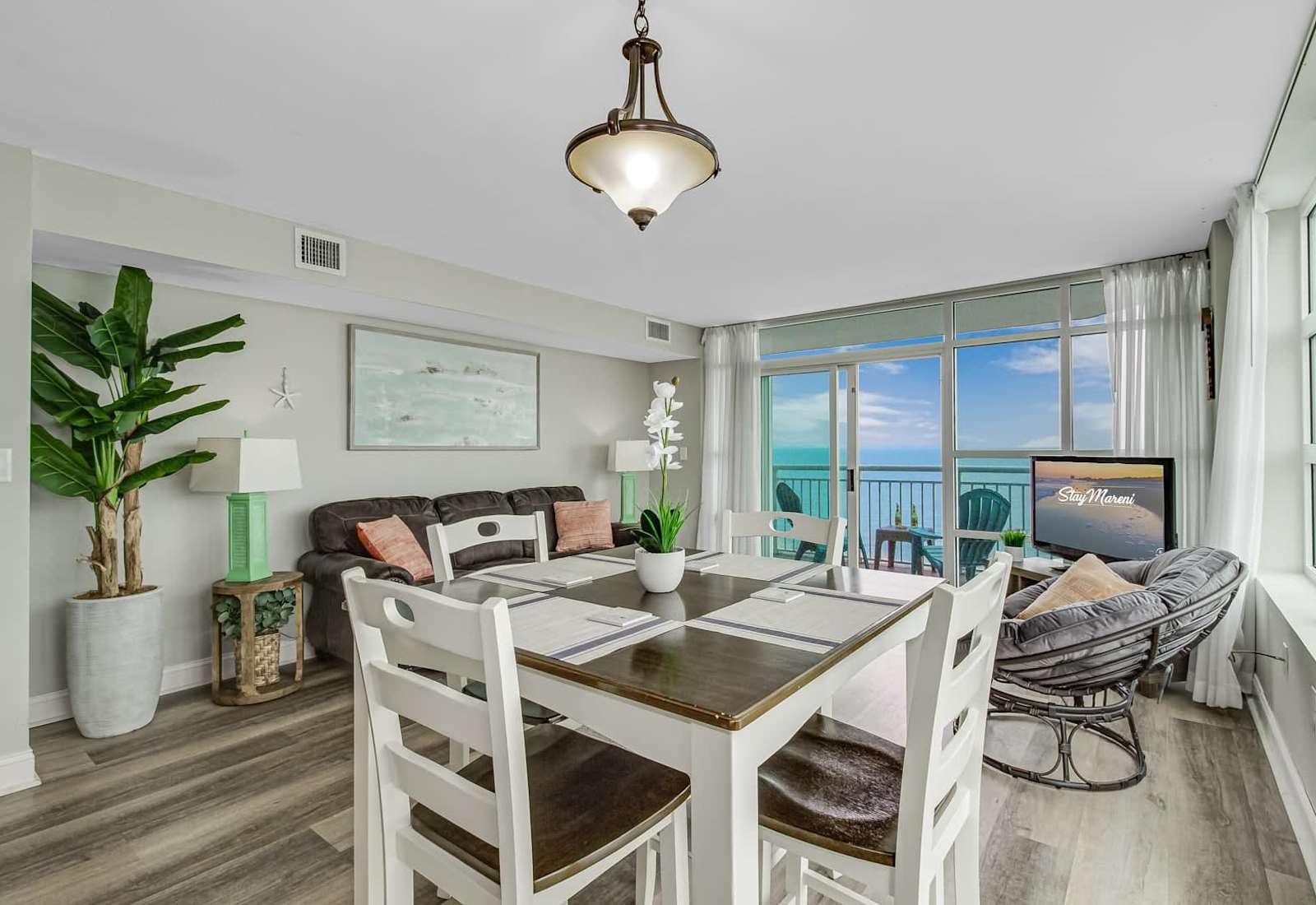 Dining and lounge space with coastal décor, comfortable seating, and floor-to-ceiling windows framing beautiful ocean views.