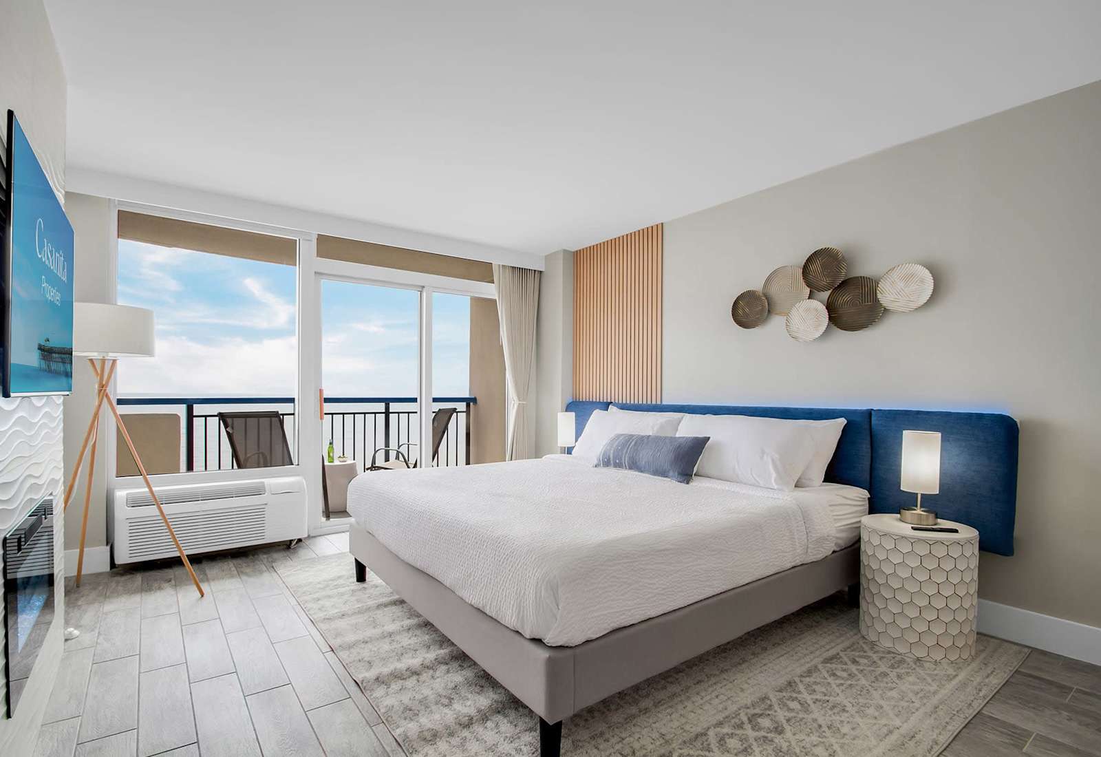 Wake up to serene ocean views in this stylish bedroom with floor-to-ceiling windows and a private balcony. Enjoy natural light, a cozy bed, modern fireplace, and sleek TV, blending comfort and luxury. Perfect for a relaxing retreat by the sea.