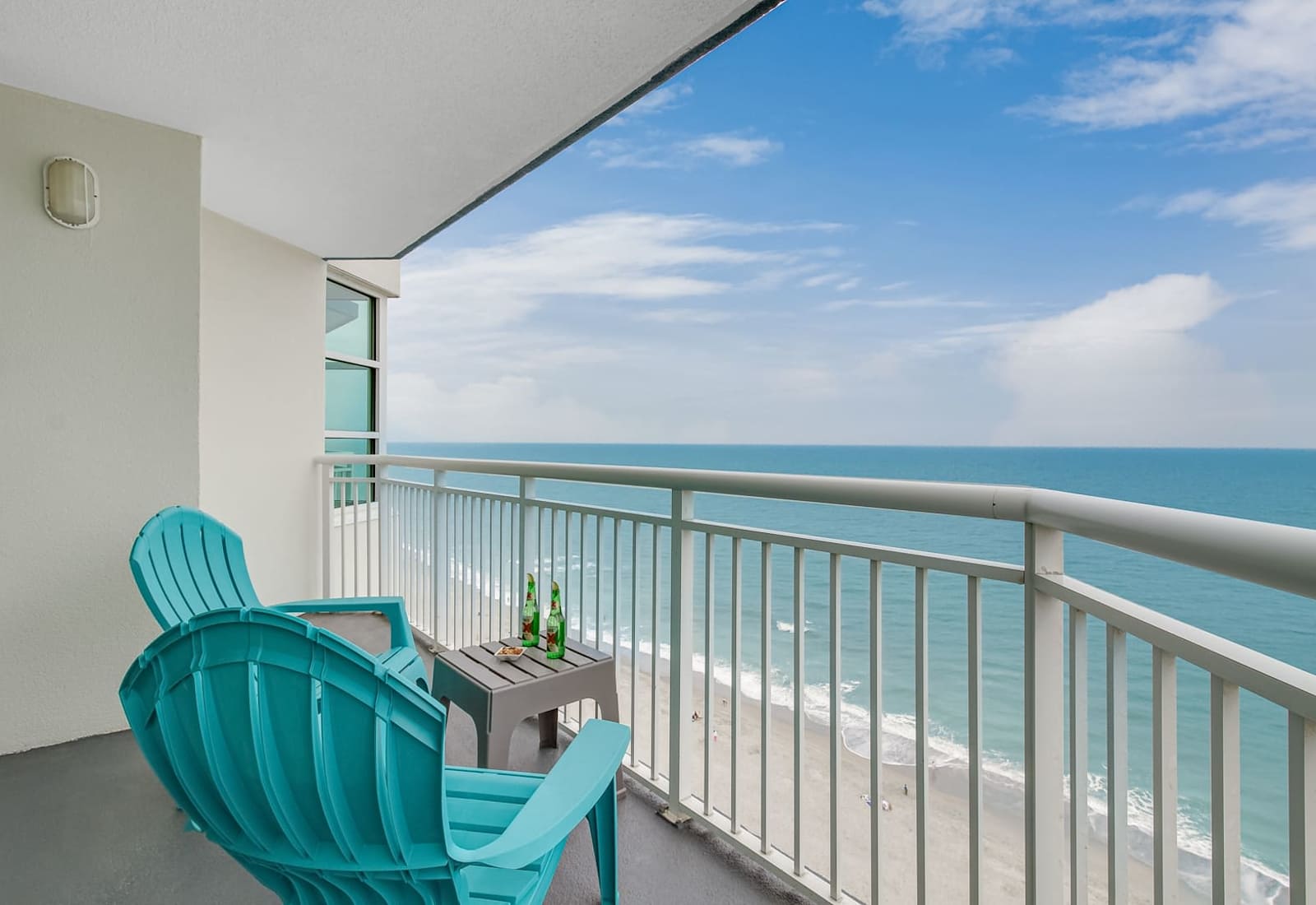 Oceanfront balcony with turquoise seating, wide water views, and a peaceful spot to unwind above the beach.