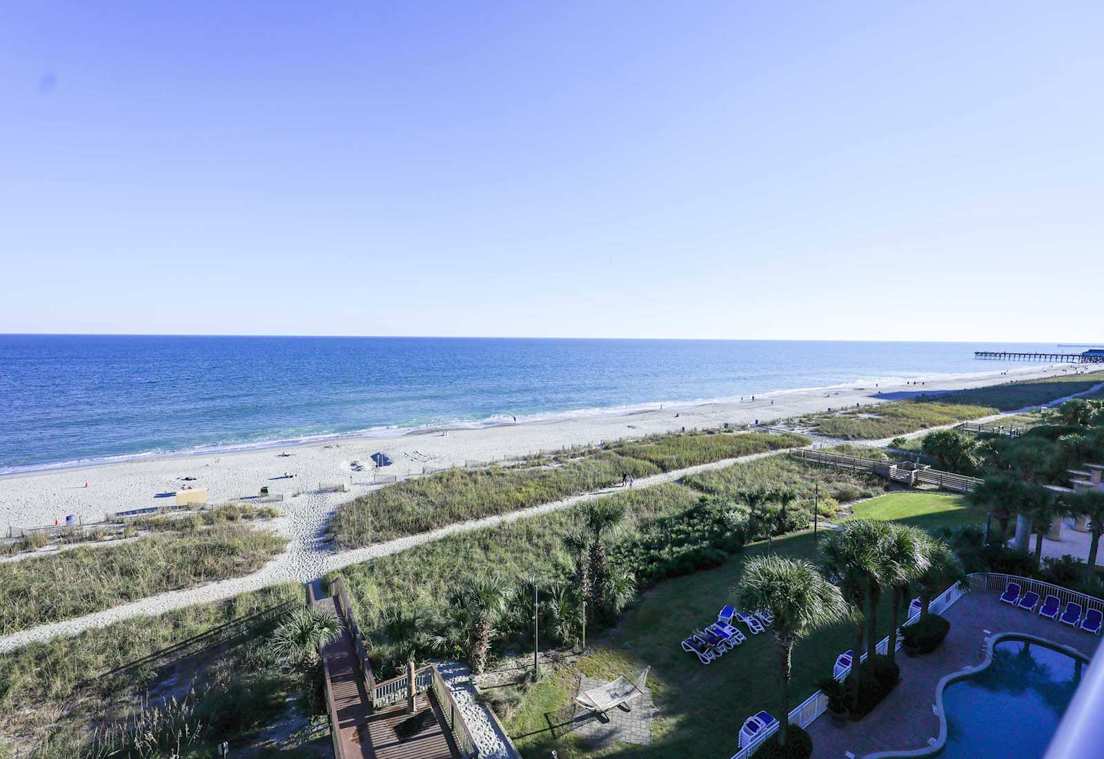 Breathtaking oceanfront view from the balcony — enjoy the sparkling blue water, soft sandy beach, and resort-style pool just steps away.