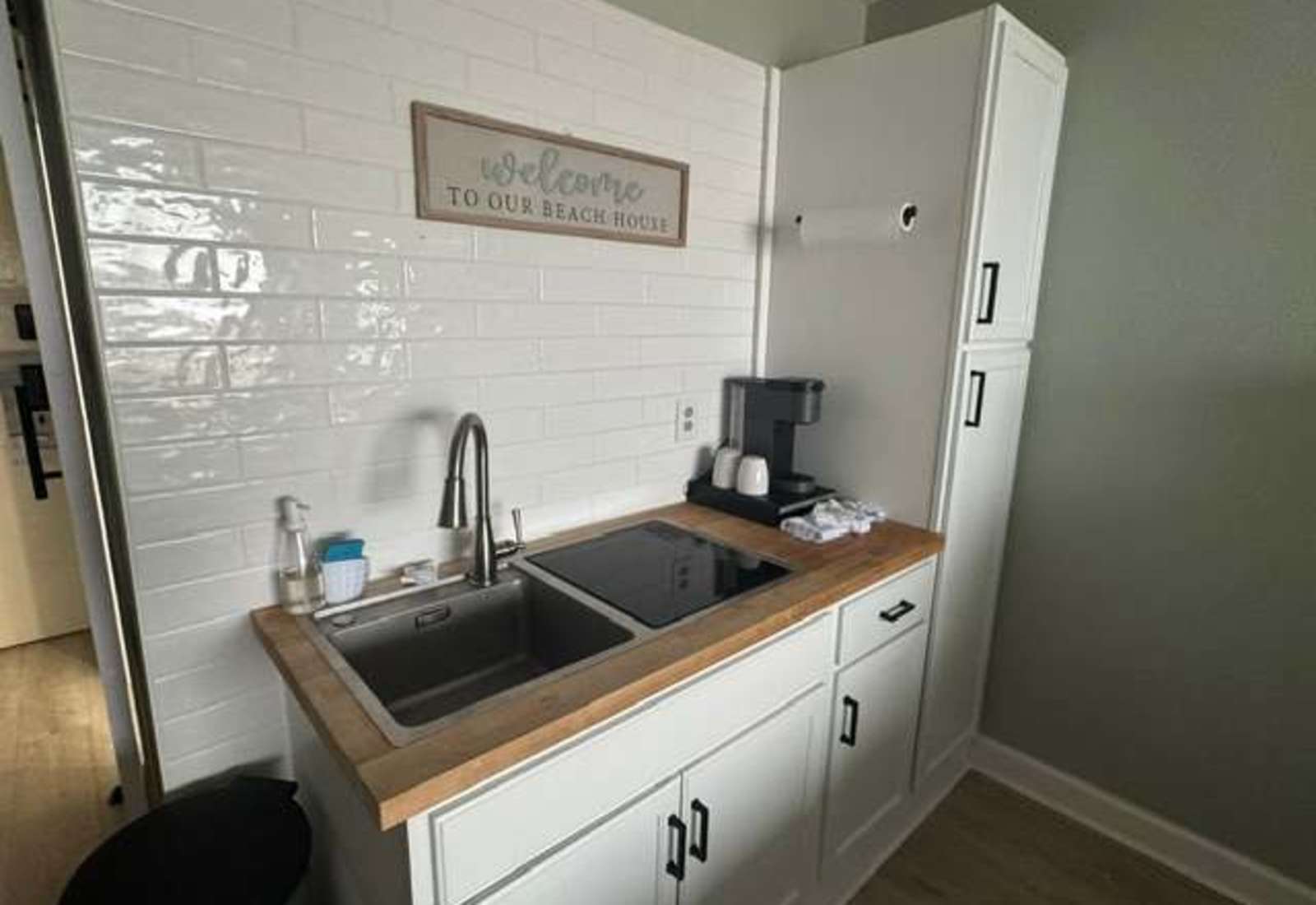 Modern kitchenette equipped with a coffee maker, sink, cooktop, and generous pantry storage