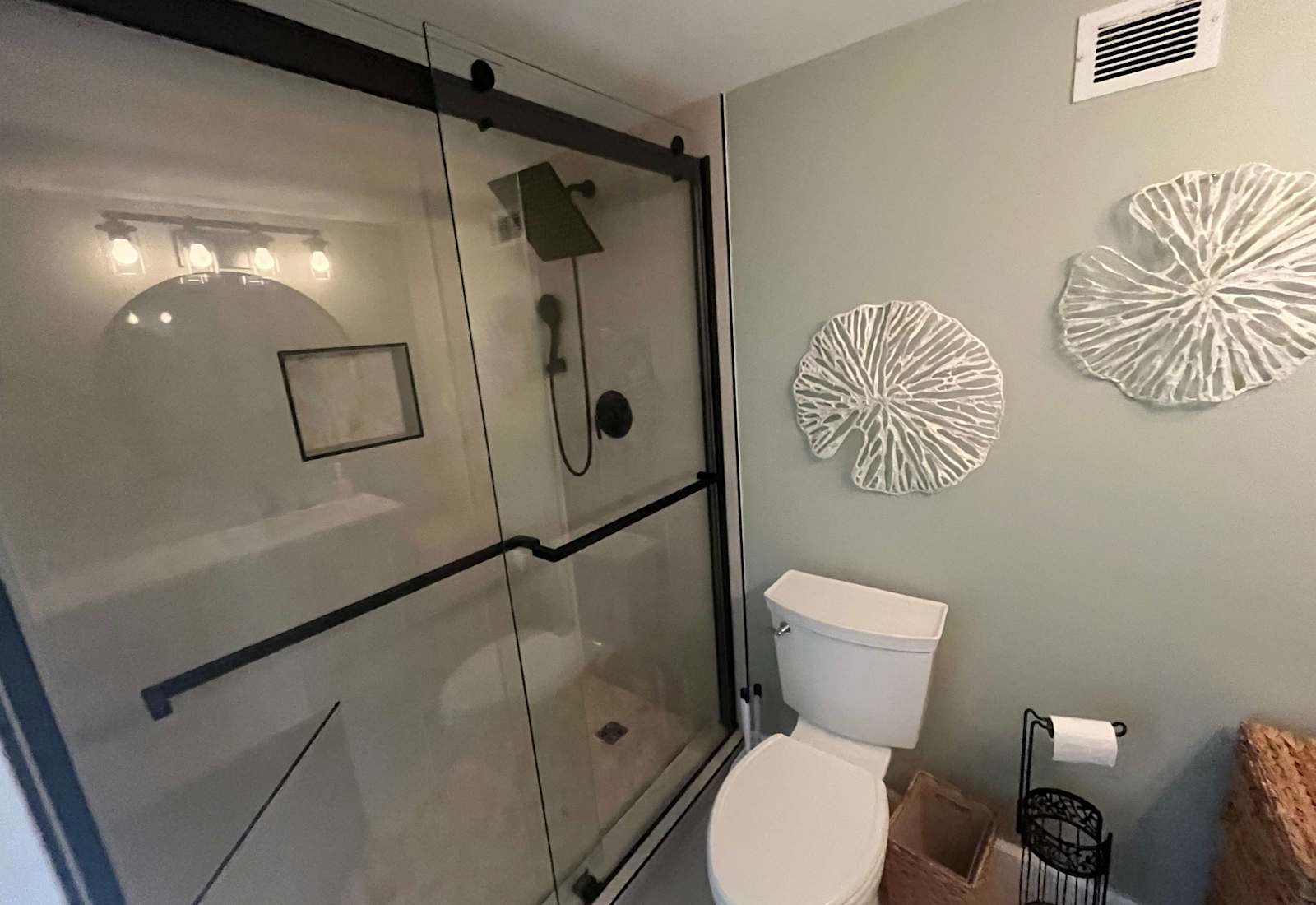 Sleek full bathroom featuring a spacious glass-door shower with modern black fixtures