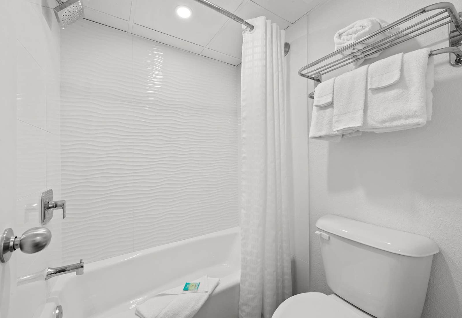 Enjoy a refreshing start or a soothing end to your day in this spotless, well-lit bathroom complete with a shower-tub combo, plush towels, and beach-inspired touches.