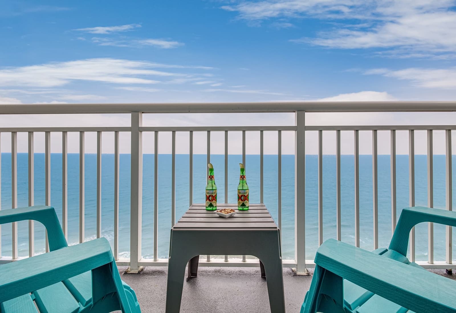 Ocean-facing balcony with seating for two, a small table, and wide-open water views that set the tone for a relaxing beach escape.