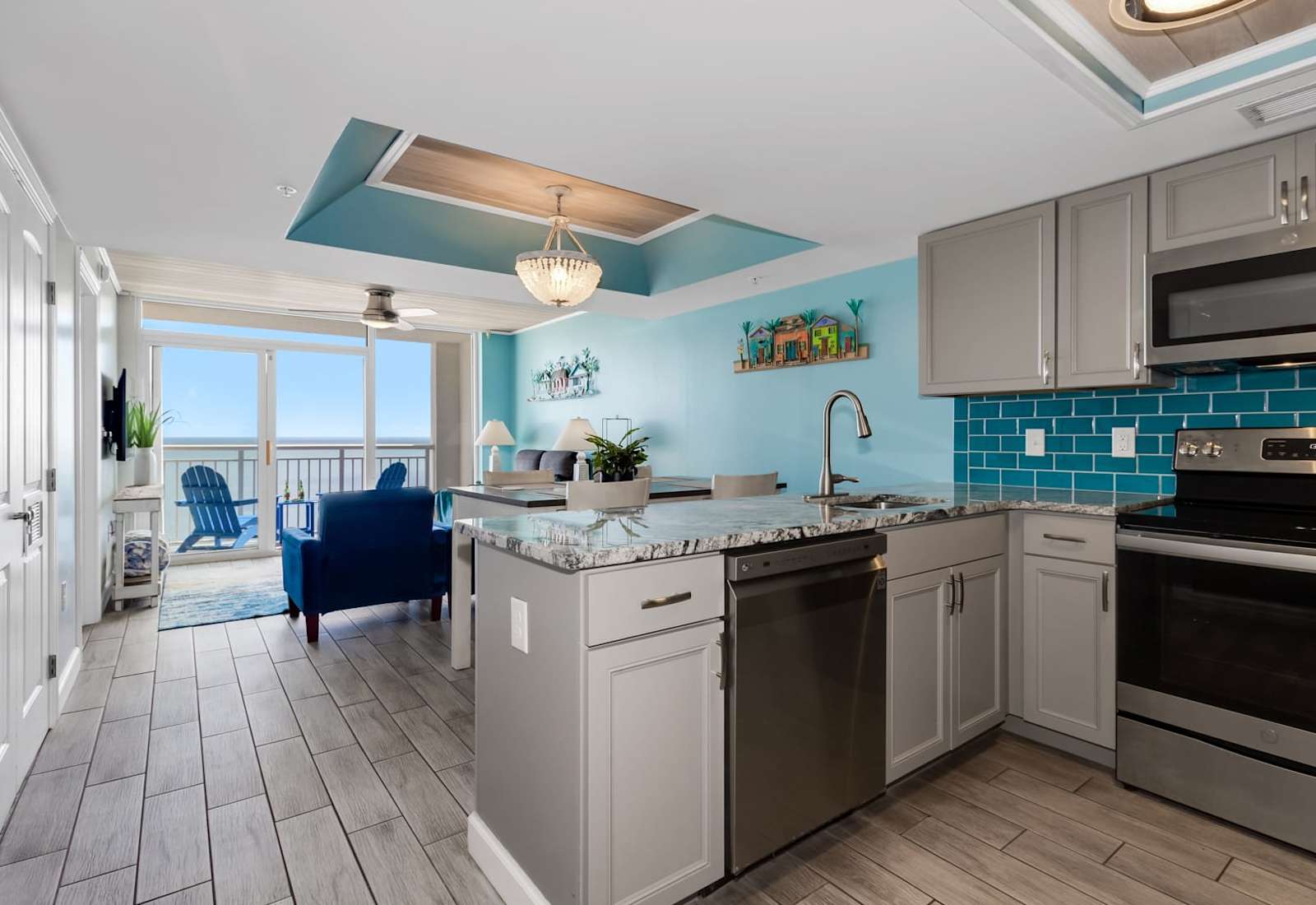 Cook and entertain in style with this open-concept kitchen featuring sleek stainless steel appliances, granite countertops, and vibrant coastal accents. Overlooking the living area and balcony, it's perfect for enjoying meals with ocean views.