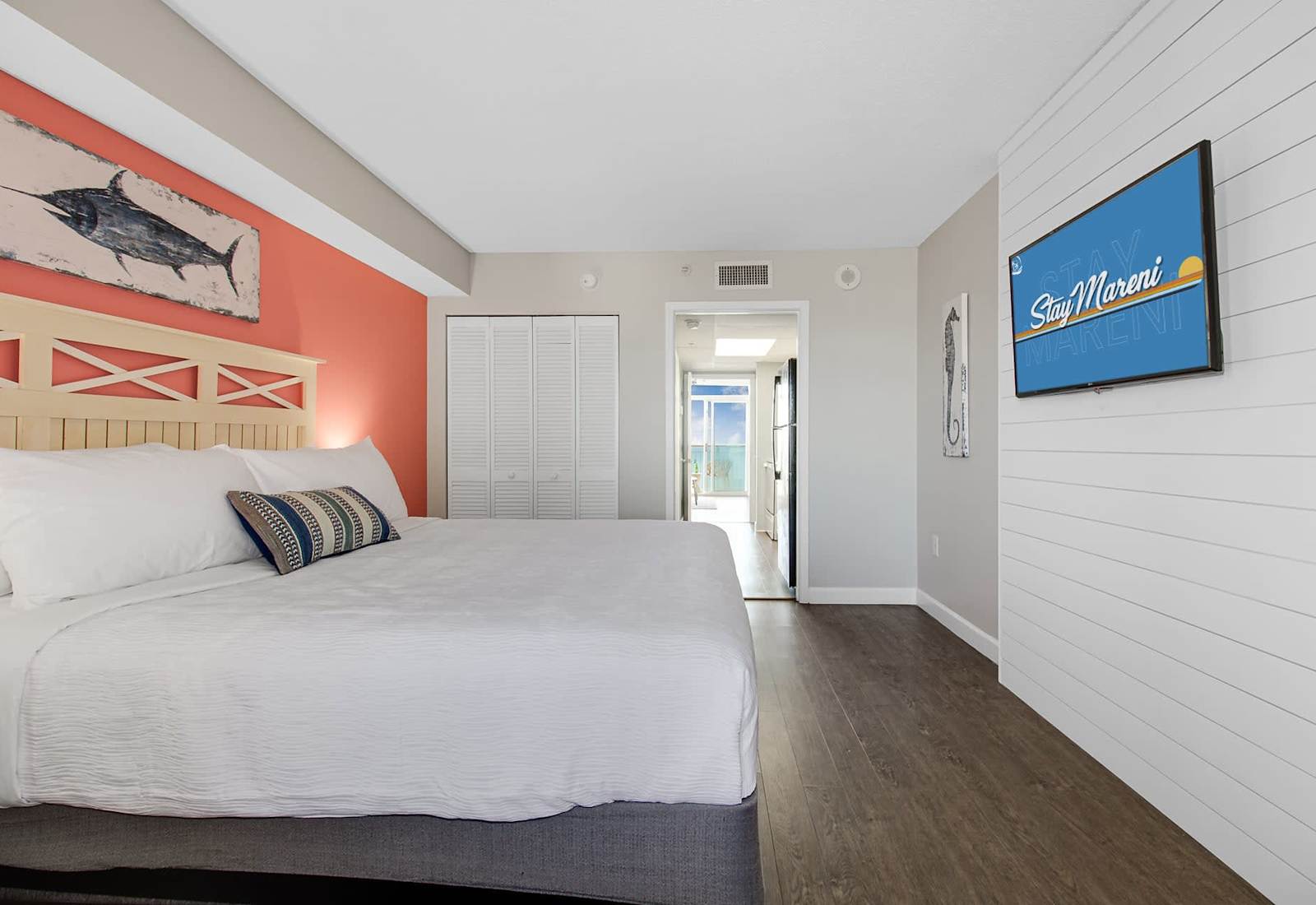 Rest easy in this vibrant and spacious bedroom featuring a plush bed, cozy coastal decor, and artistic wall accents that capture the essence of a beach getaway. With comfort and style in every detail, it’s the perfect space for a peaceful retreat