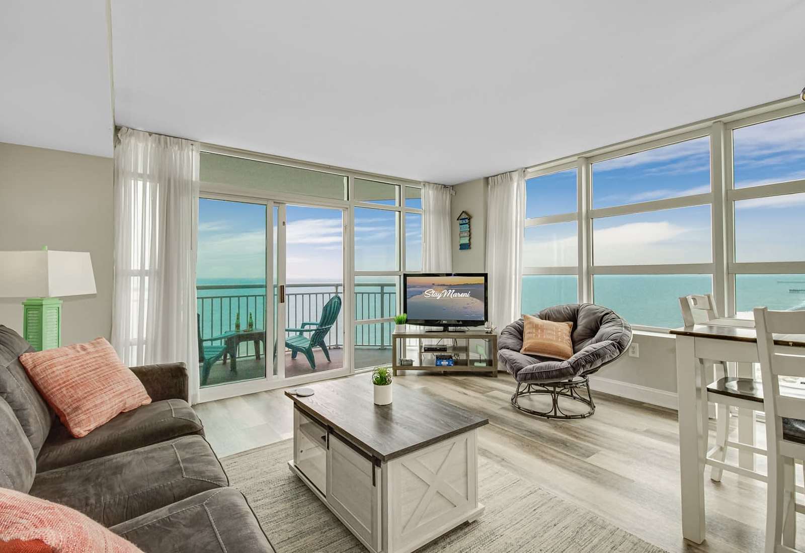 Bright coastal lounge with comfortable sofas, soft natural light, and easy balcony access for enjoying the beachfront scenery.