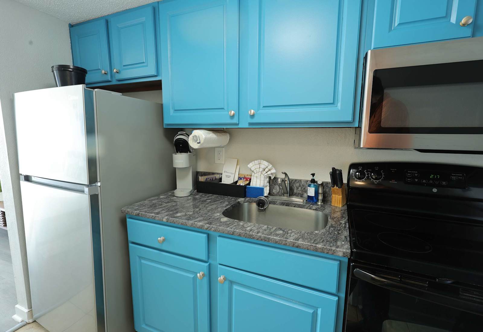 Compact and cheerful kitchenette with bright coastal-blue cabinets, full-size appliances, a Keurig, and the essentials for easy meals during your Myrtle Beach stay.