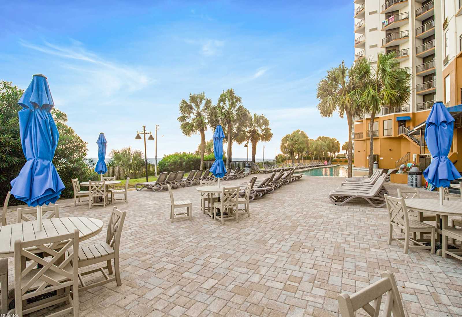 Enjoy the coastal breeze on this spacious outdoor patio, perfect for lounging in the sun or sharing a meal under the shade. Just steps from the beach and pool, it's your go-to spot for relaxation and connection.