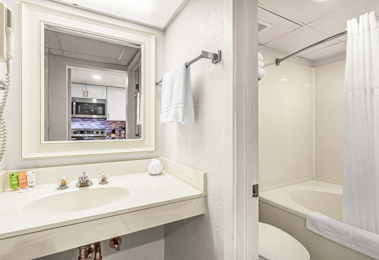 
Refresh in this spotless bathroom featuring a wave-textured wall, sleek tub, and plush towels.