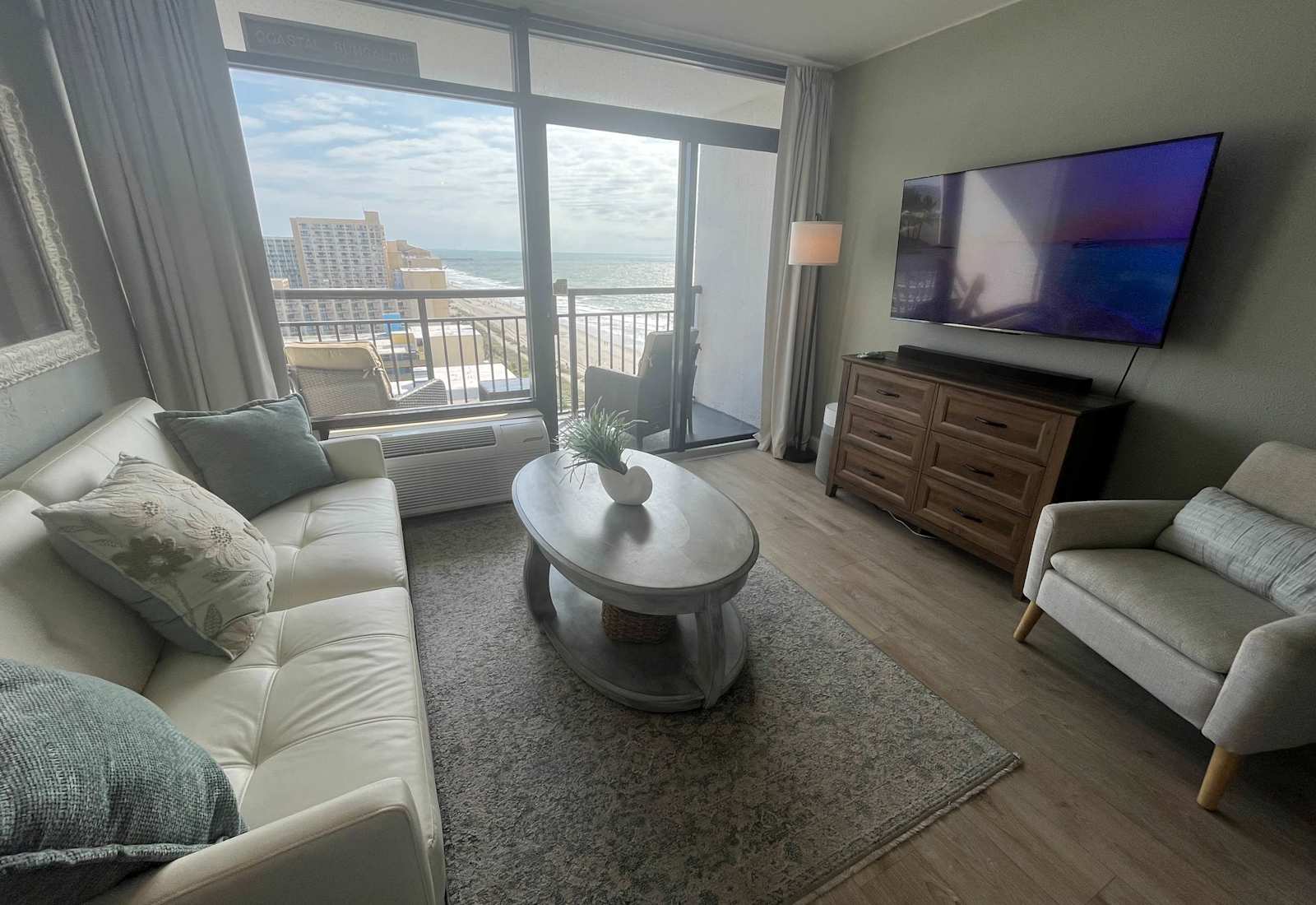 Relaxing living space featuring a large smart TV and direct balcony access with ocean views