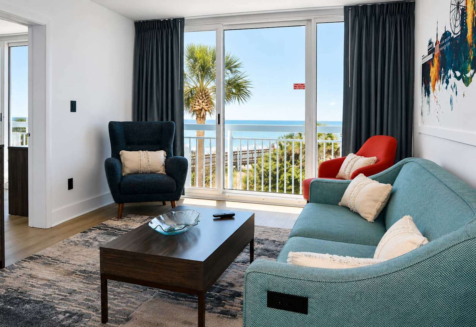 Unwind on our plush teal sofa right beneath the stunning watercolor skyline mural!