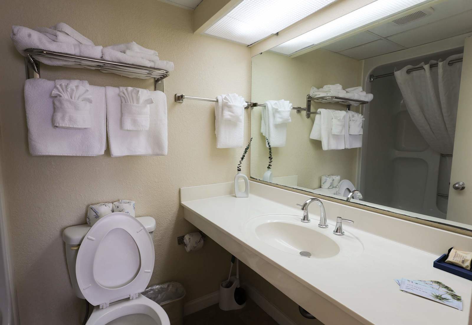 A clean, well-appointed bathroom featuring neatly arranged towels, plush 14lb terry linens, and a bright vanity setup, complemented by upscale toiletries for a comfortable, hotel-quality stay.