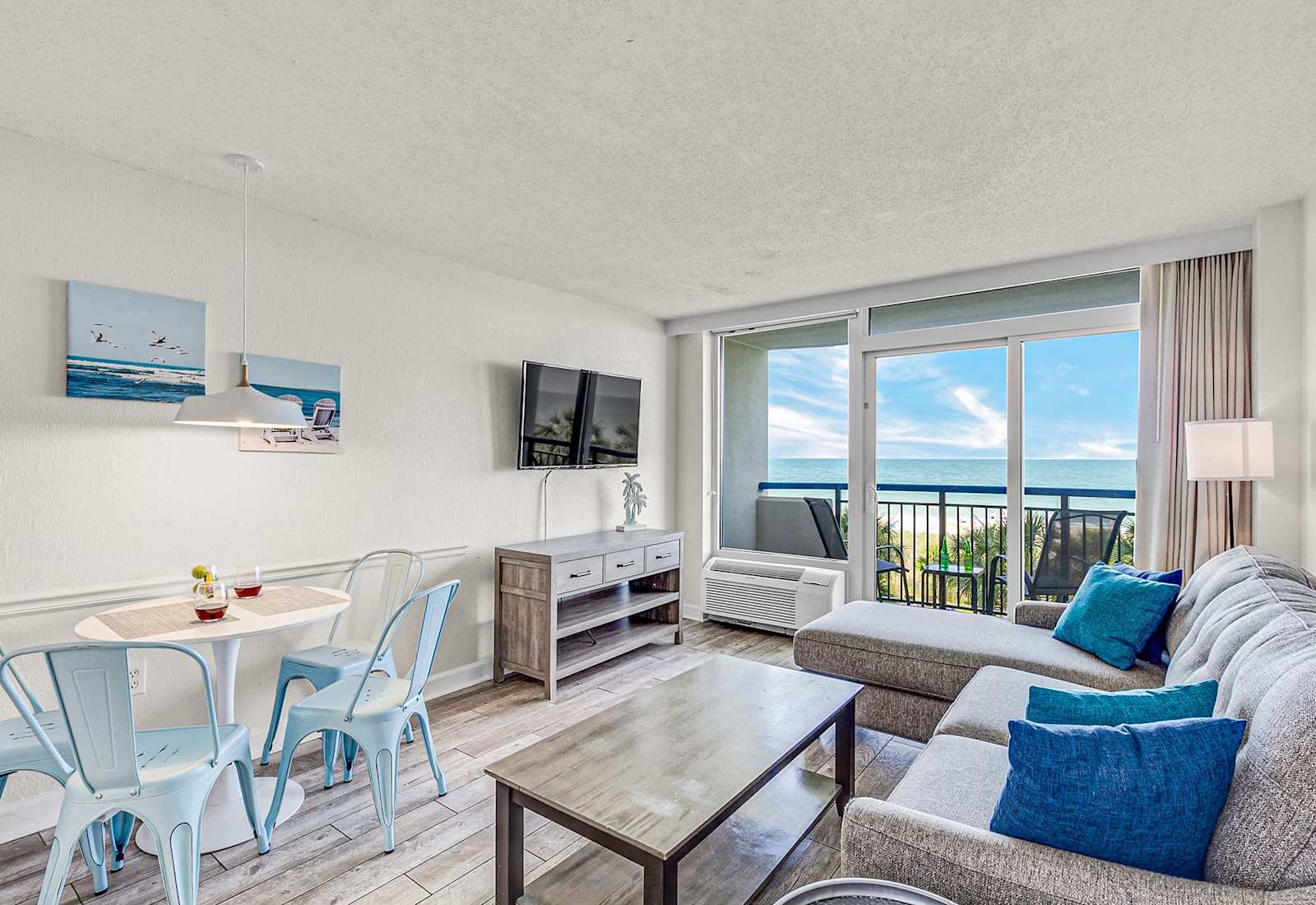 Oceanfront comfort meets modern style — unwind in this bright, coastal living space featuring panoramic beach views, a cozy sectional, and a private balcony perfect for morning coffee or sunset relaxation.