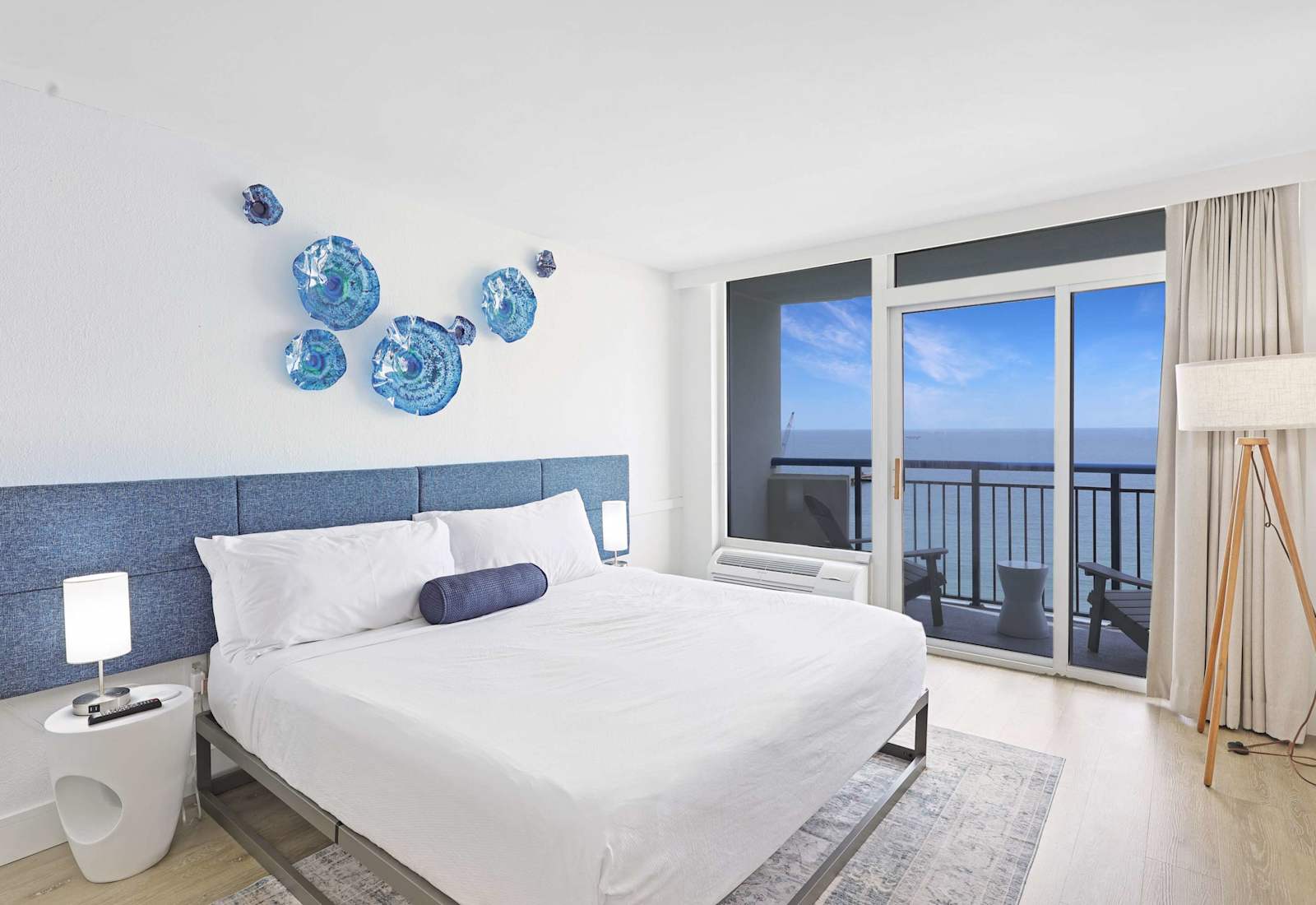 Inviting bedroom with a cozy King bed, vibrant seaside décor, and private balcony access.