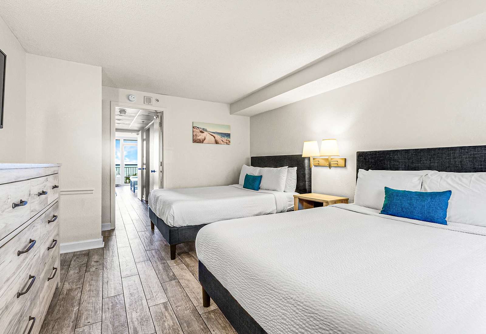 Wake up to ocean views in this bright, coastal bedroom featuring two plush beds, soft linens, and beach-inspired décor—perfect for relaxing after a sun-filled day on the shore.