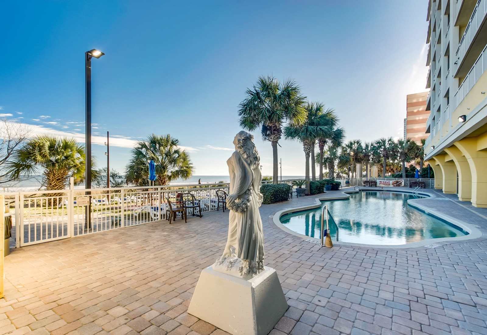 Relax by the pool with stunning ocean views and a serene atmosphere, complemented by beautiful sculptures and palm-lined paths. Enjoy the peaceful surroundings and easy access to beach fun, making your stay truly memorable. 
