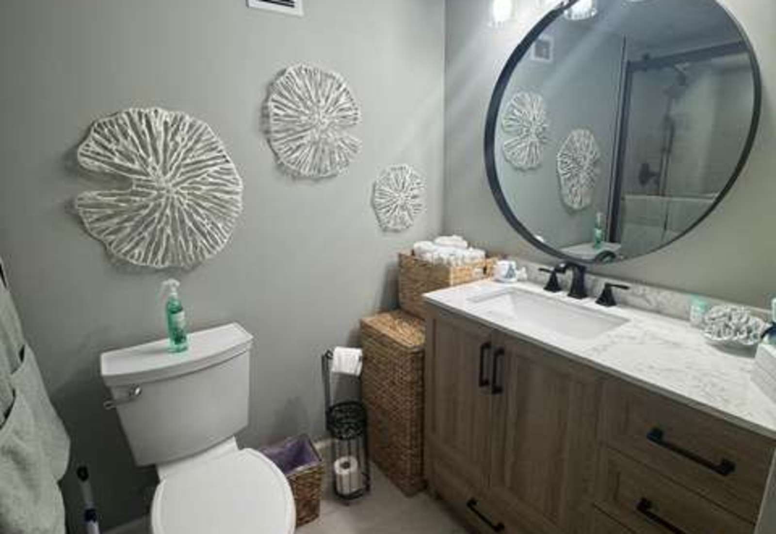 Stylish bathroom vanity with a large round mirror, stone countertop, and modern lighting