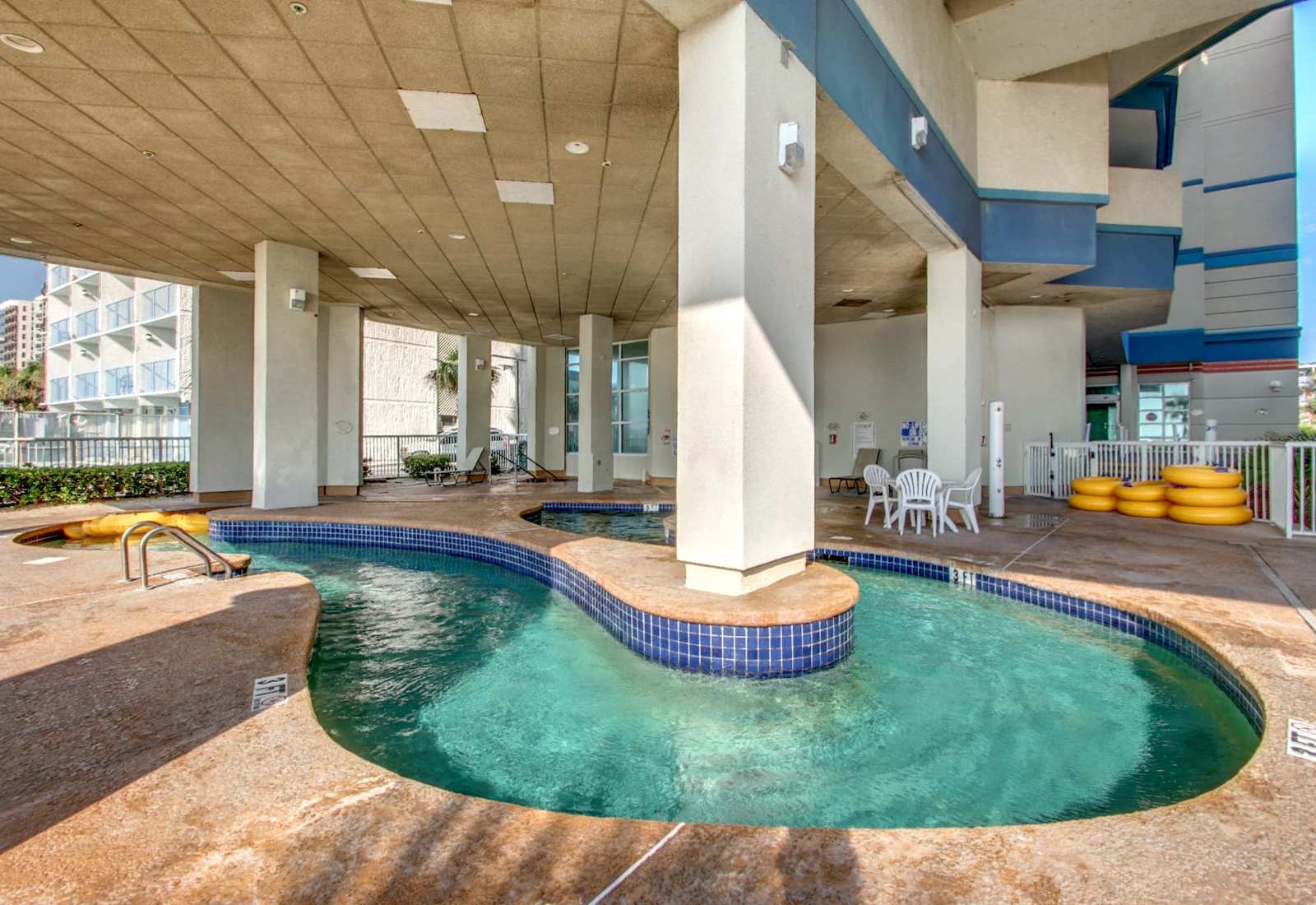 Covered resort pool area with shaded seating, swim spaces, and easy access for a refreshing break from the sun.
