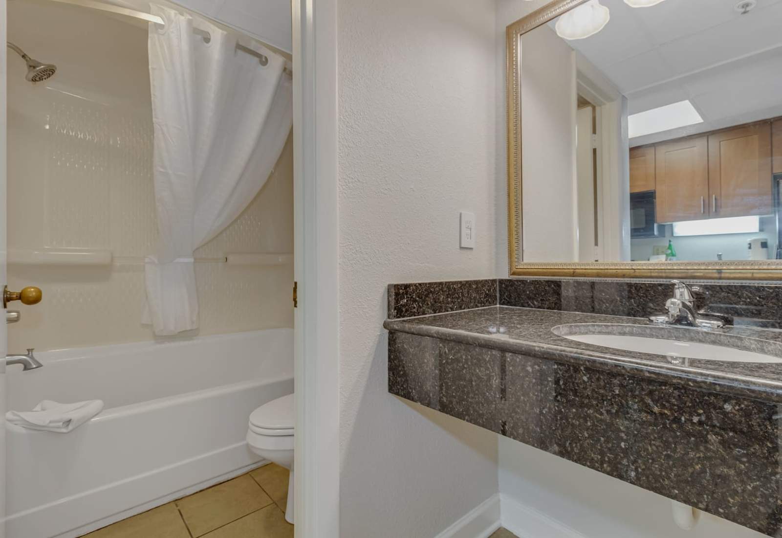 Bright and airy bathroom with a bathtub/shower combo, granite countertop vanity, and plenty of natural light. 